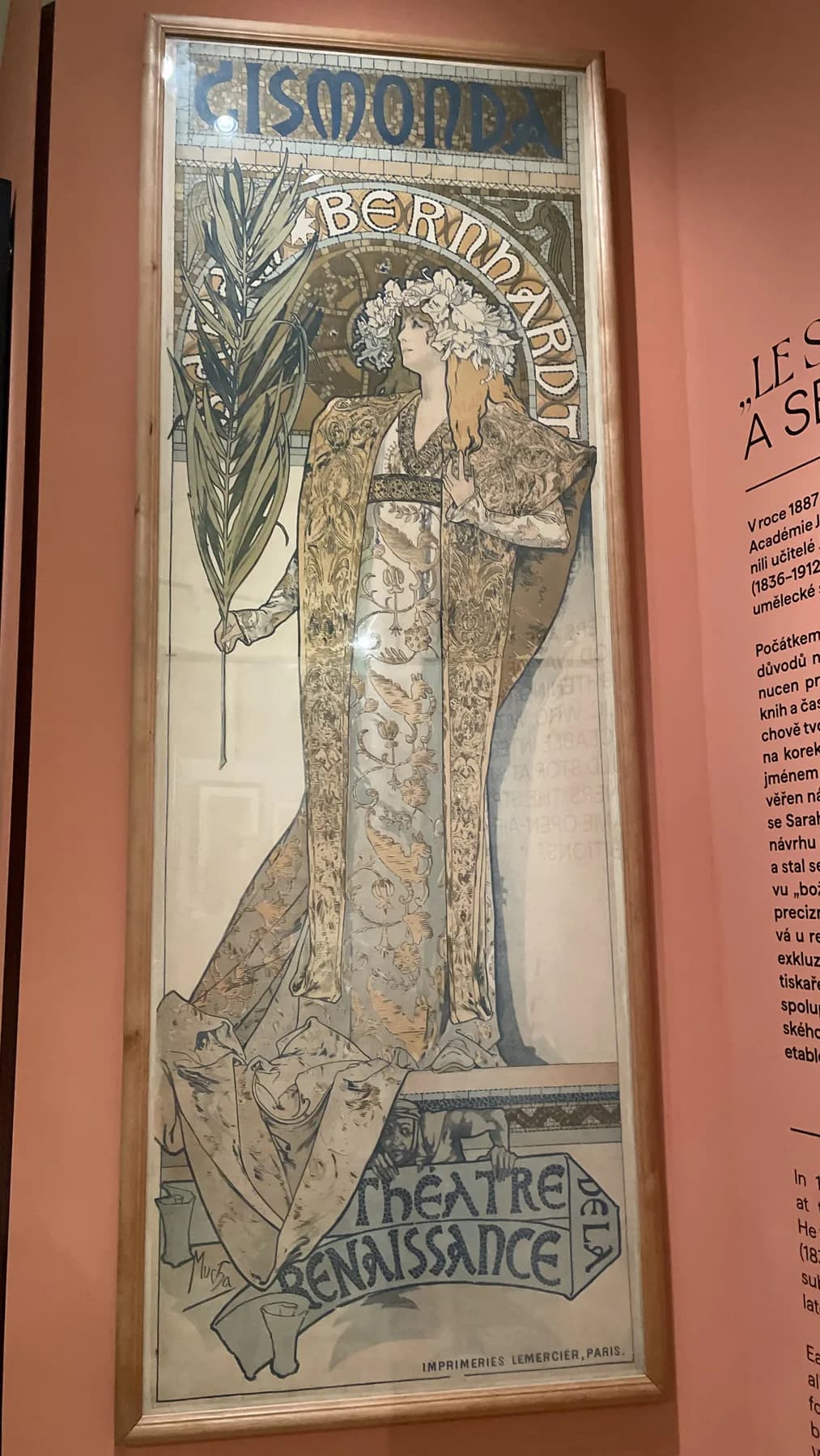 Alphonse Mucha's Gismonda poster for Sarah Bernhardt displayed in an exhibition, with the figure, lettering, ornamental frame, and theatre name visible.